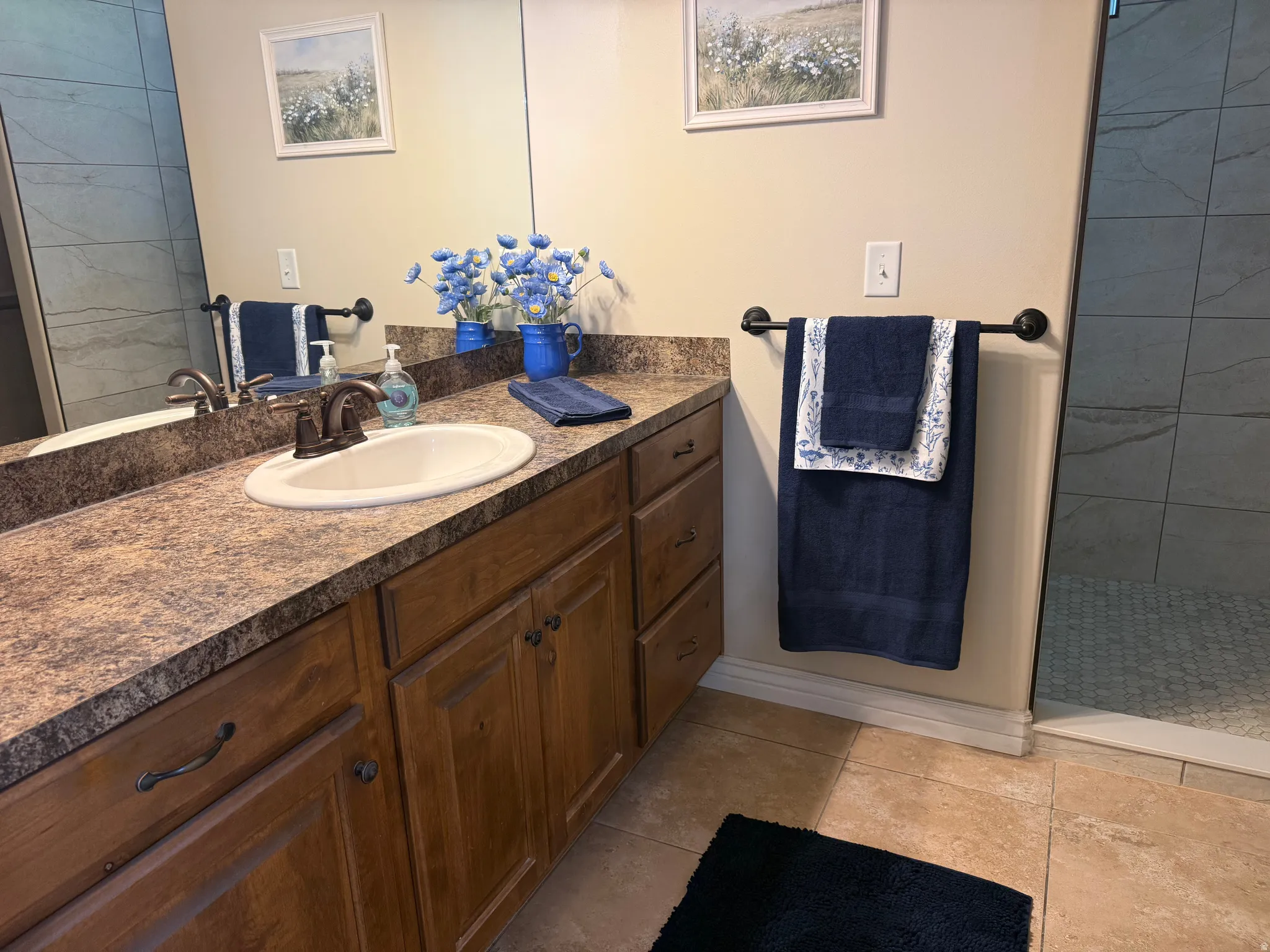 Bathroom vanity featuring a single sink with a bronze-finish faucet, an expansive countertop, and wood-finish cabinetry