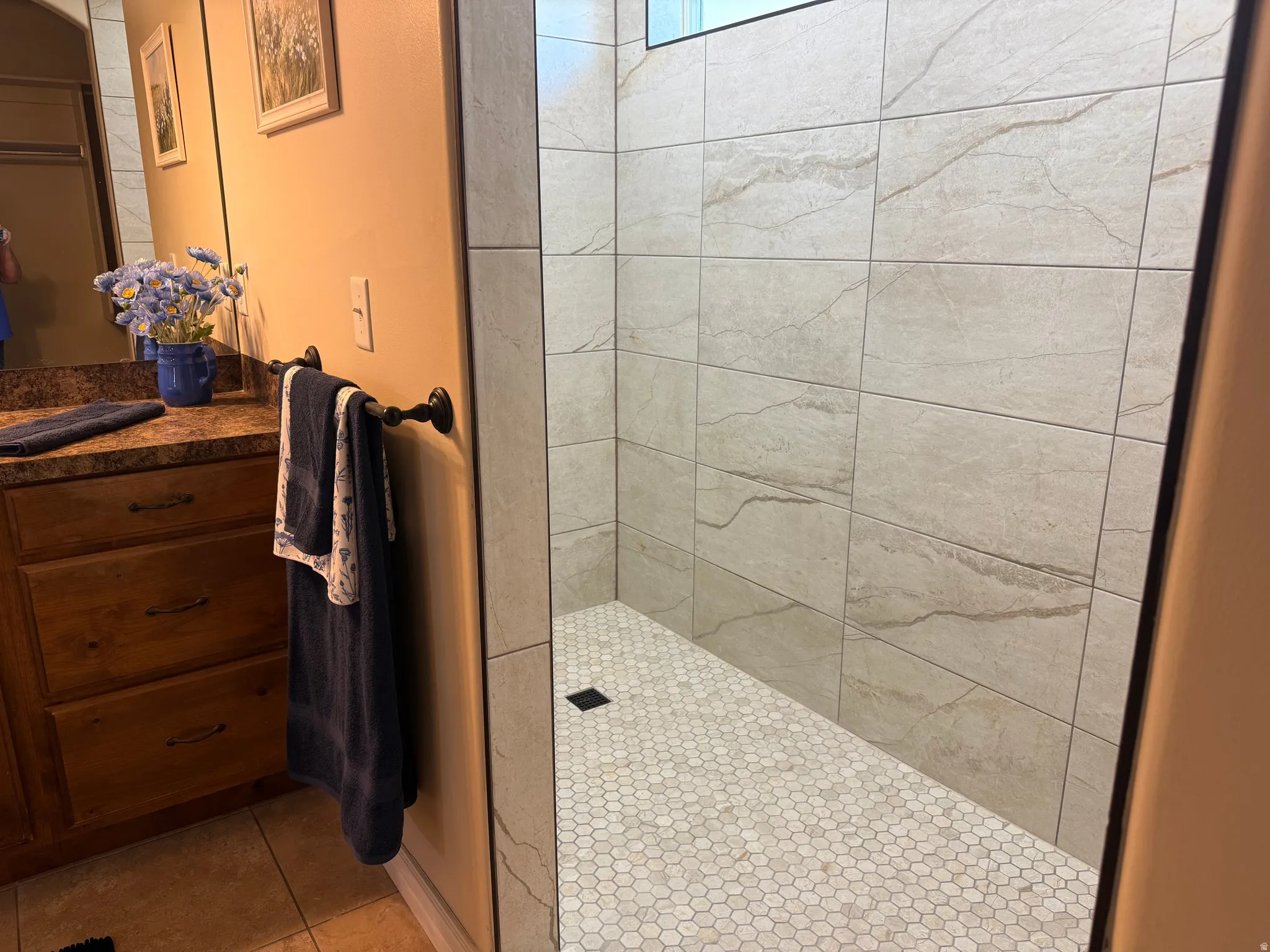 Walk-in shower featuring large-format stone-look wall tiles and a hexagonal tile floor