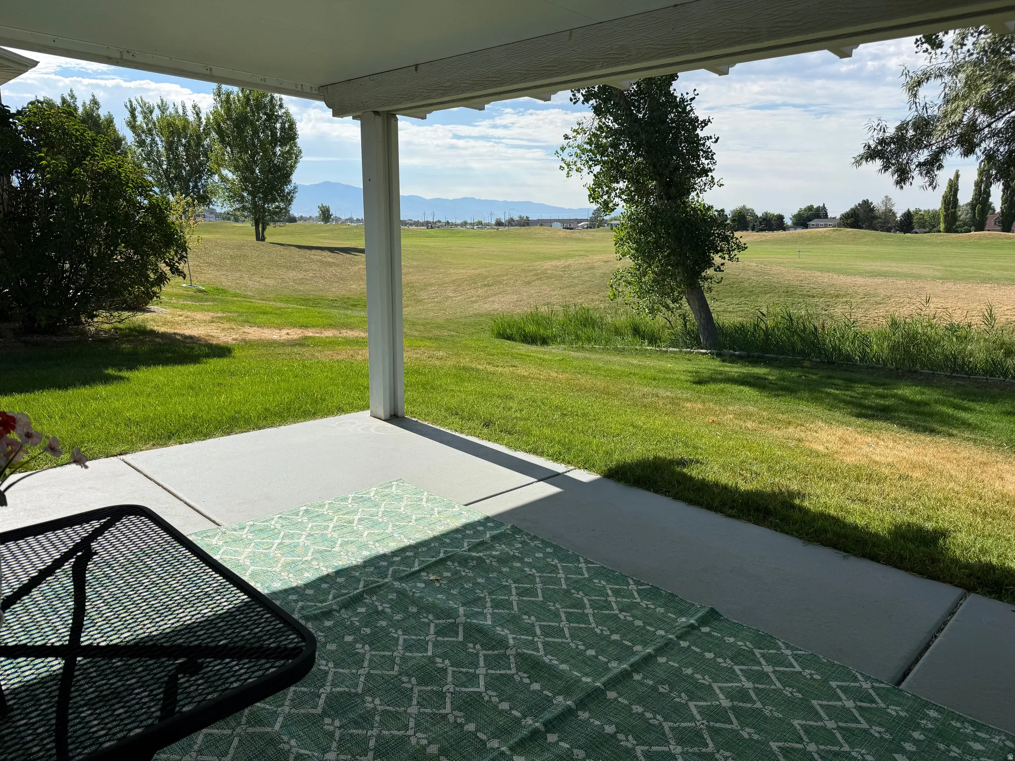 Covered concrete patio overlooking an expansive green space with distant mountain scenery
