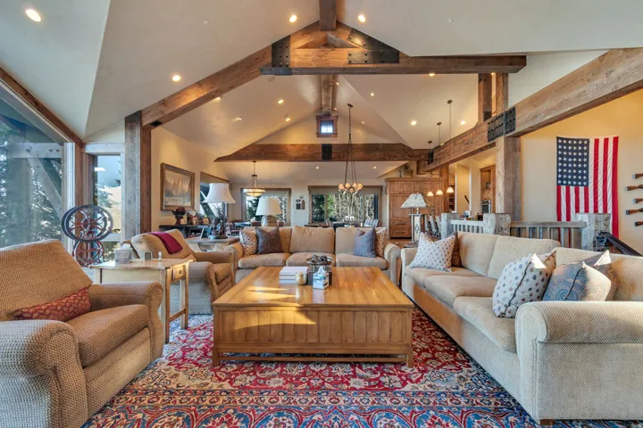 Spacious living area featuring exposed wood beams, vaulted ceilings, expansive windows, recessed lighting, and a built-in wooden coffee table
