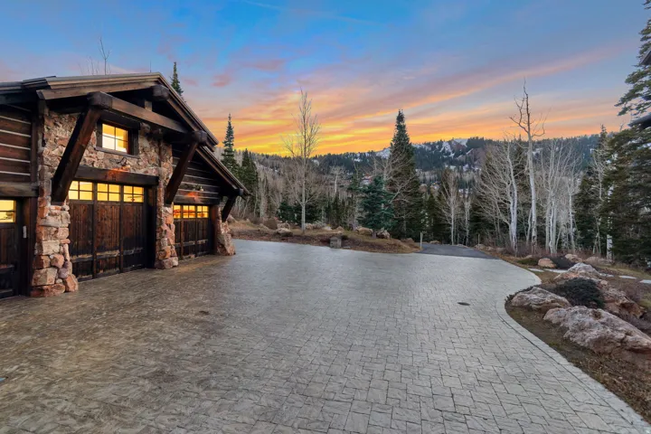 Rustic-style garage featuring stone and timber construction with wood garage doors