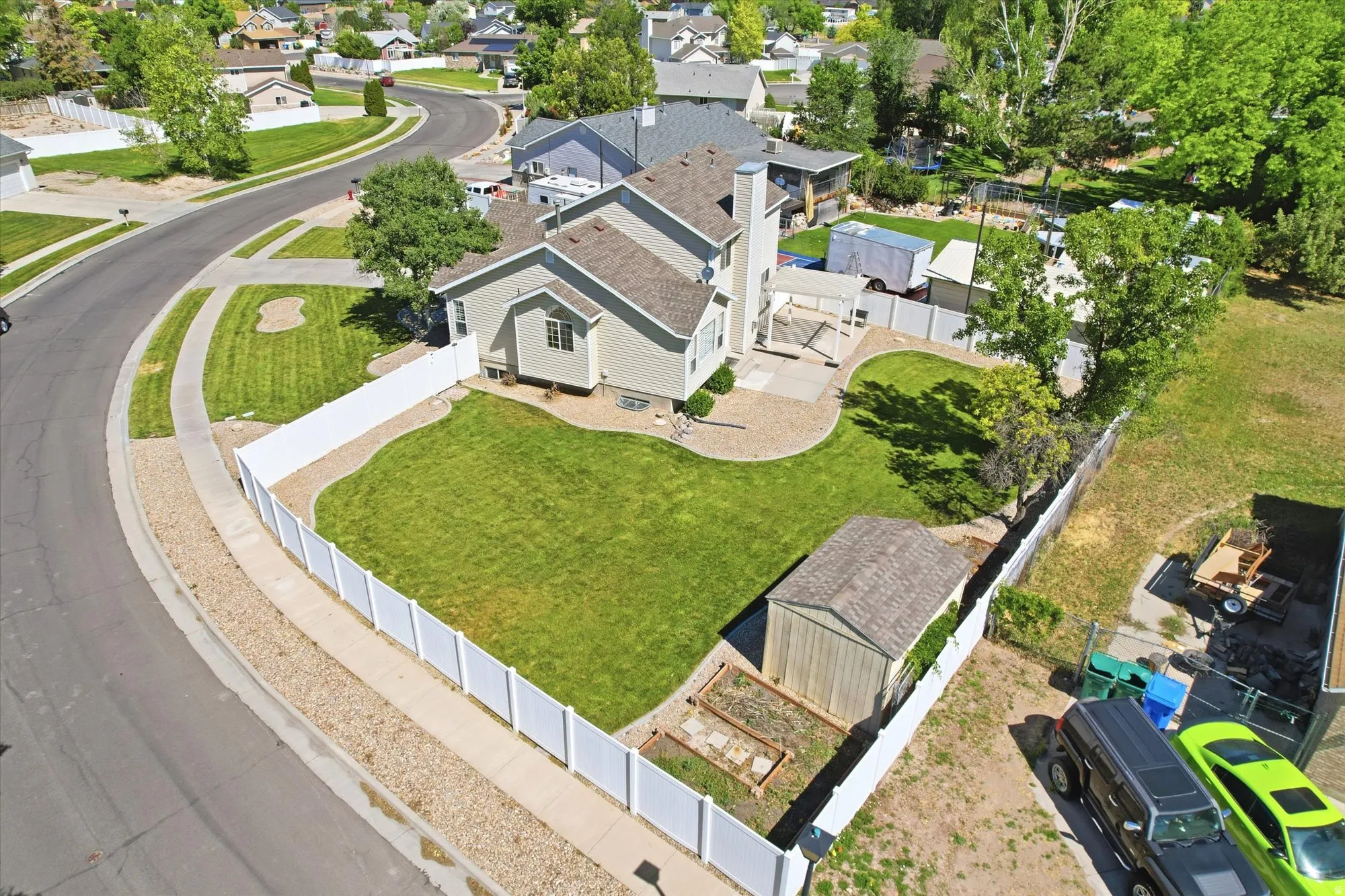 Expansive fenced backyard featuring a manicured lawn, established trees, and a dedicated storage shed