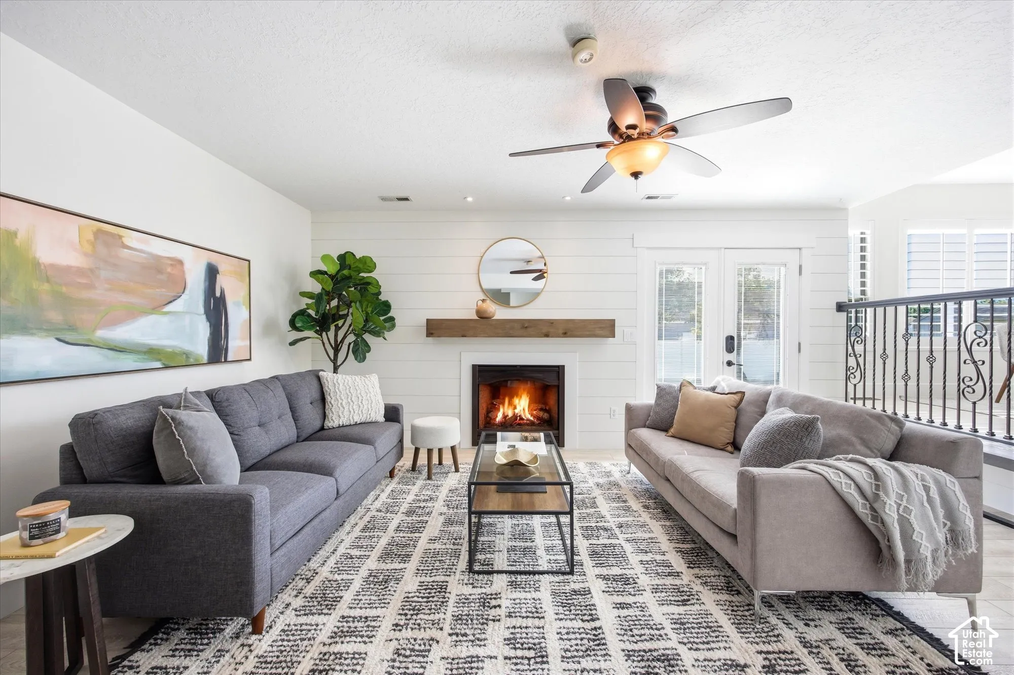 Living area featuring a fireplace with a wood mantel, shiplap accent wall, and double glass-paneled doors