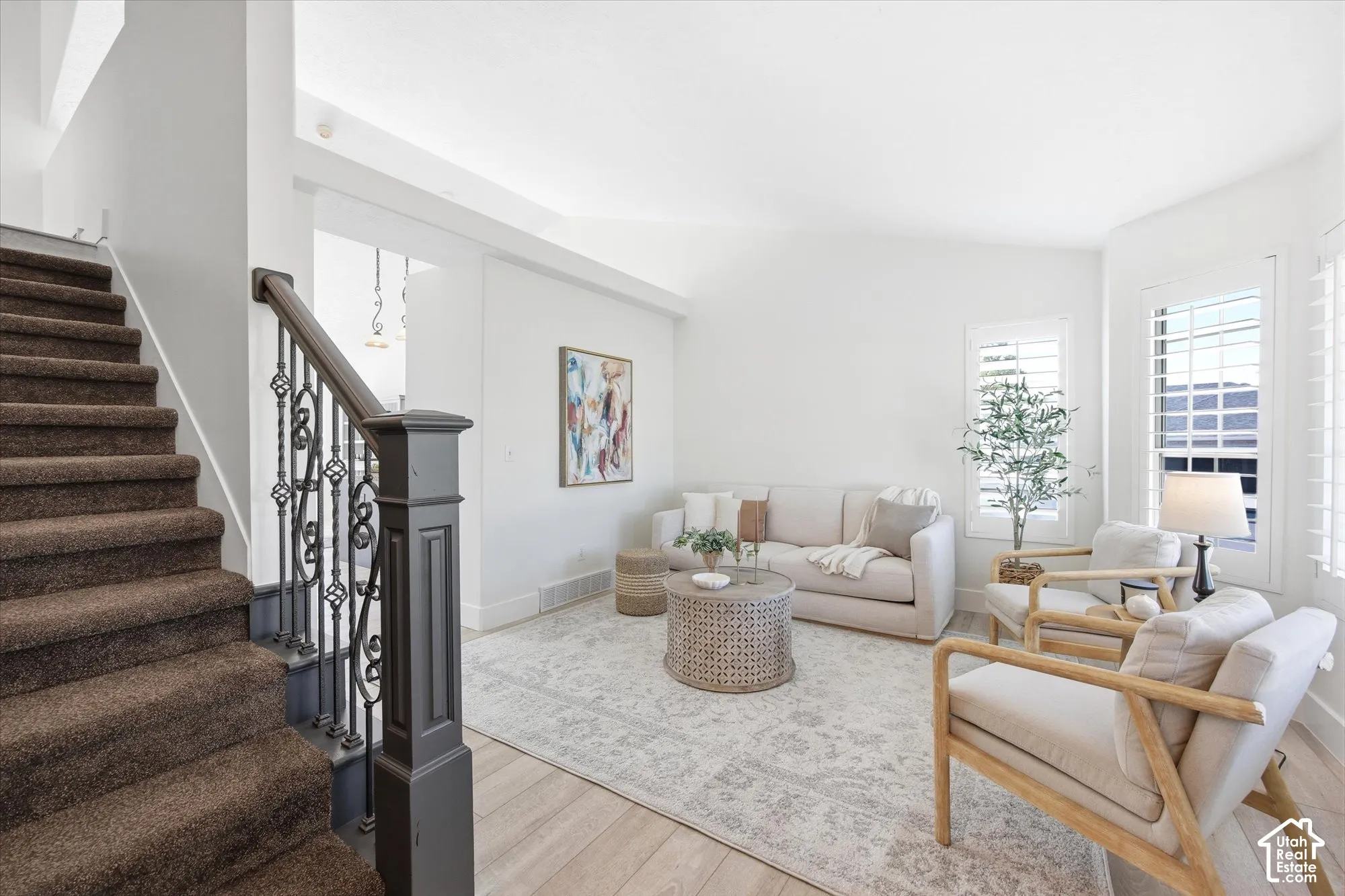 Inviting living area featuring light wood-finish flooring, plantation shutters, and a white color palette