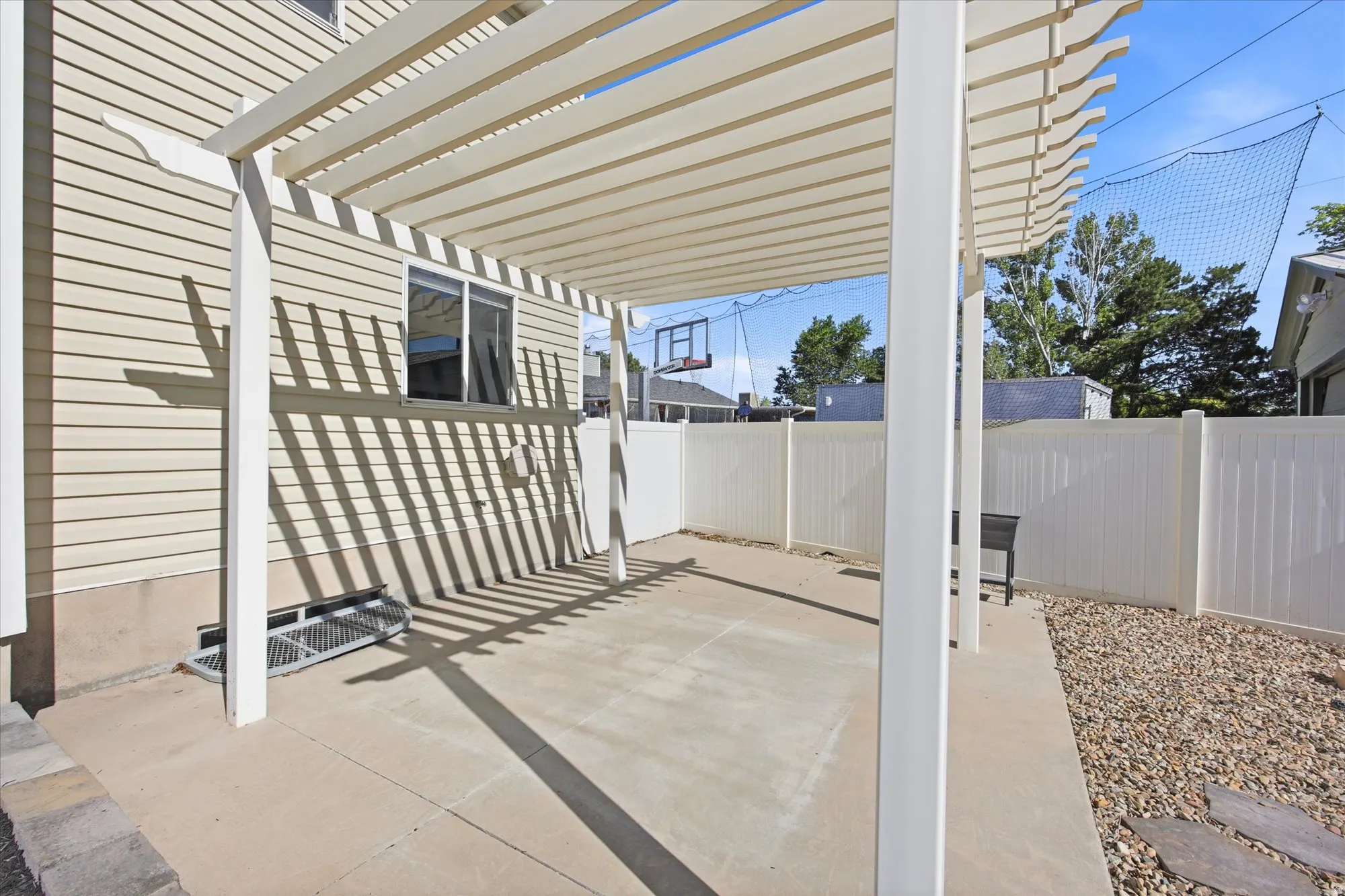 Rear patio featuring a pergola, concrete surface, and white privacy fencing