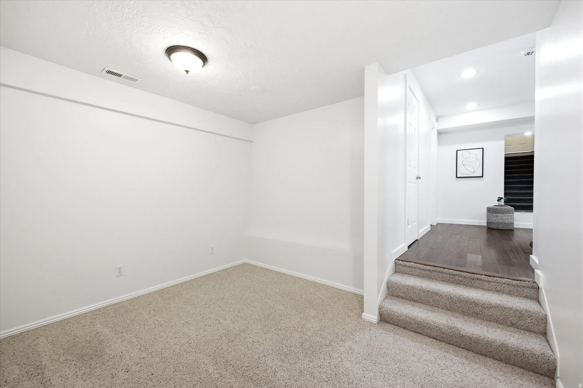 Carpeted room featuring a ceiling-mounted light fixture and baseboard trim
