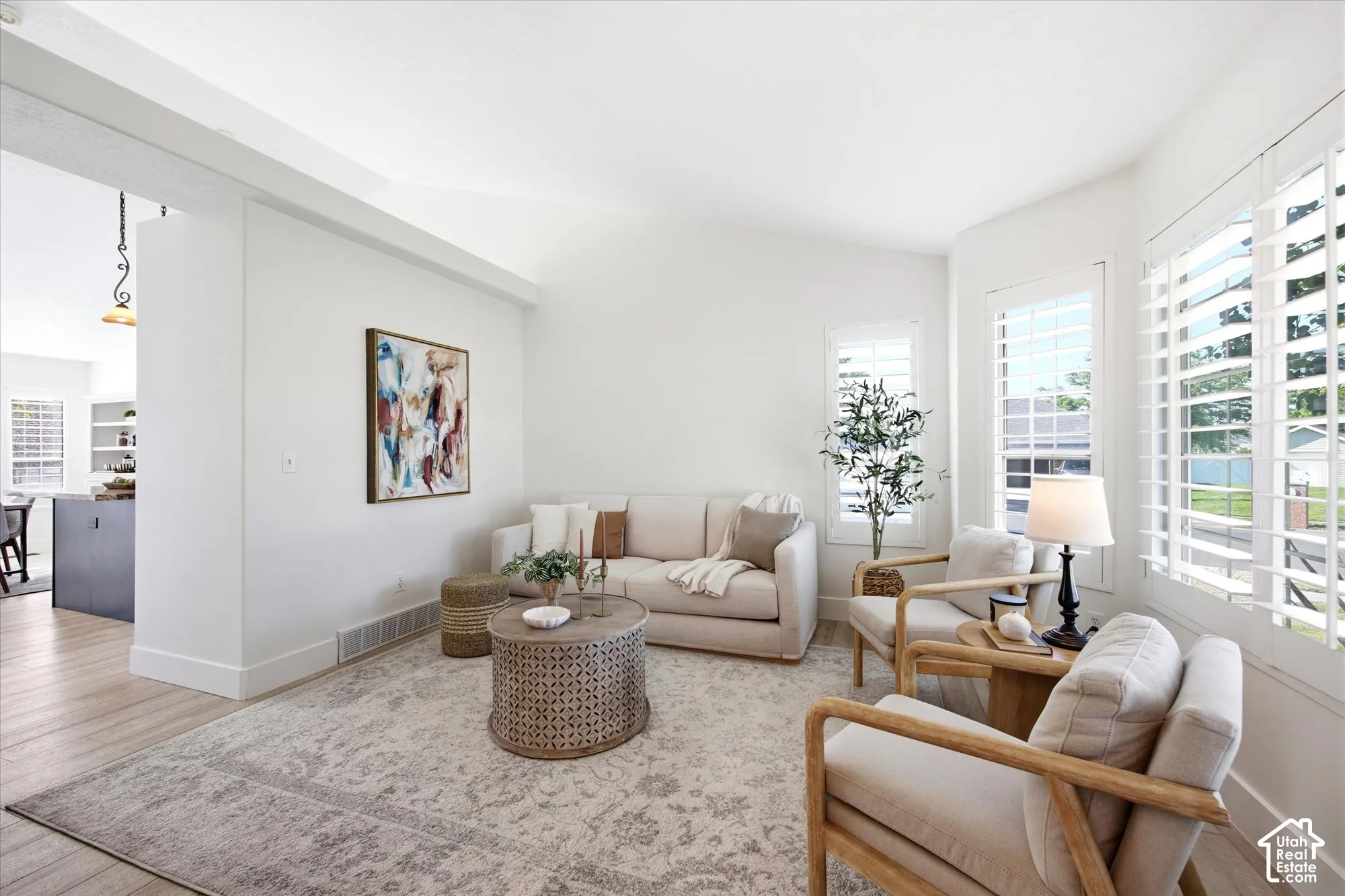 Bright living area featuring white walls, vaulted ceilings, and wood-finish flooring