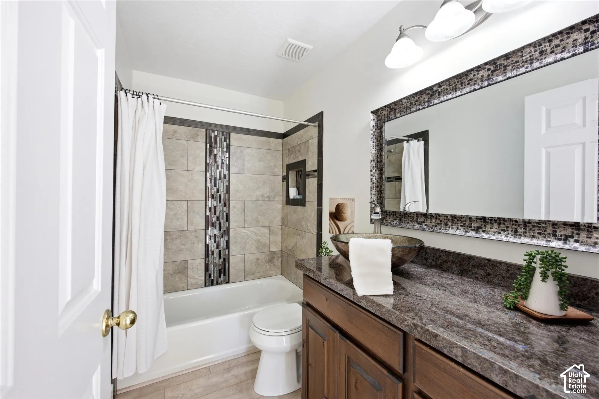 Bathroom featuring a tub/shower combination with mosaic tile accent, dark wood-finish vanity with stone-finish countertop, and vessel sink