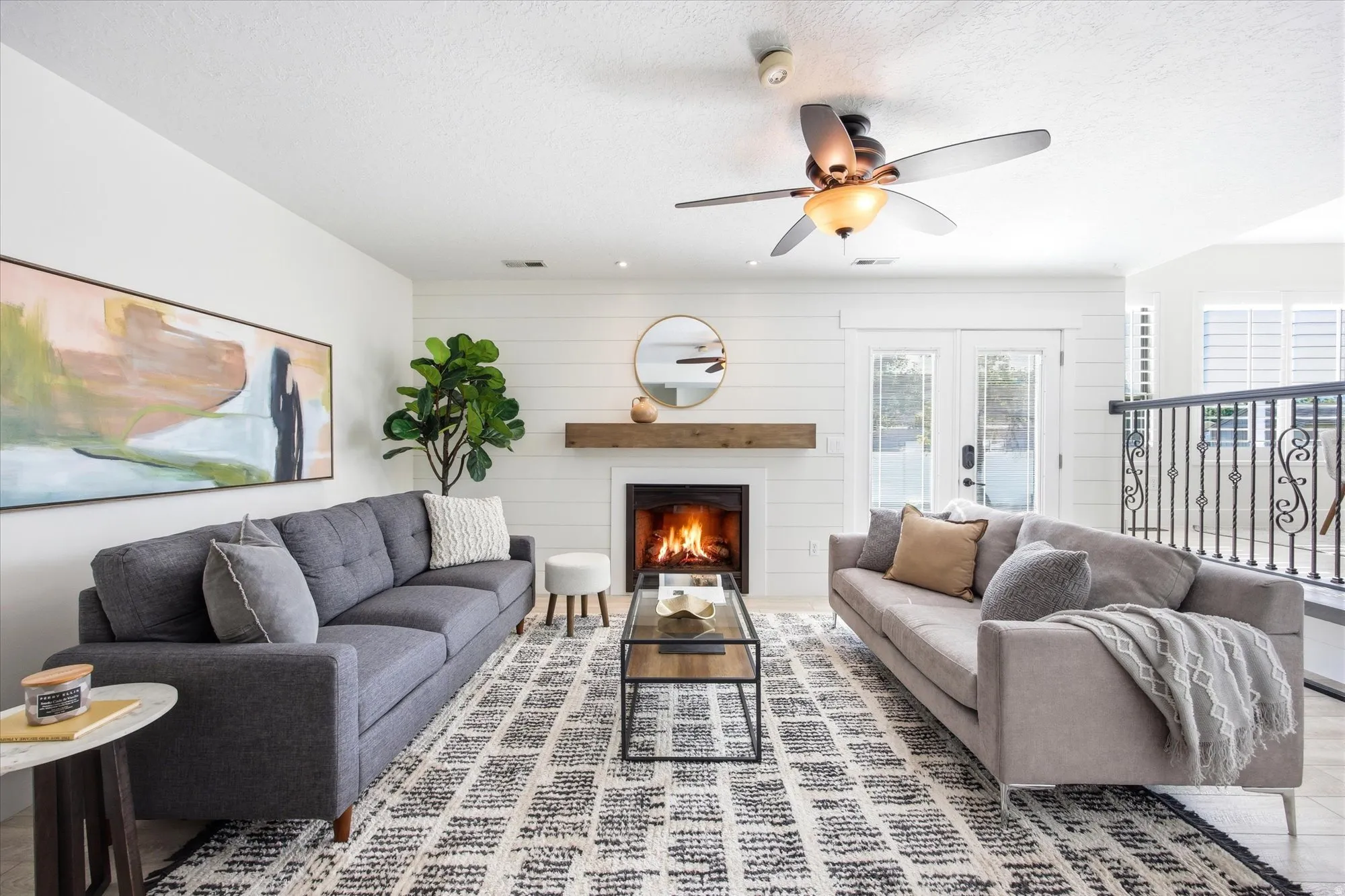 Living area featuring a fireplace with a wood mantel, shiplap accent wall, and double glass-paneled doors