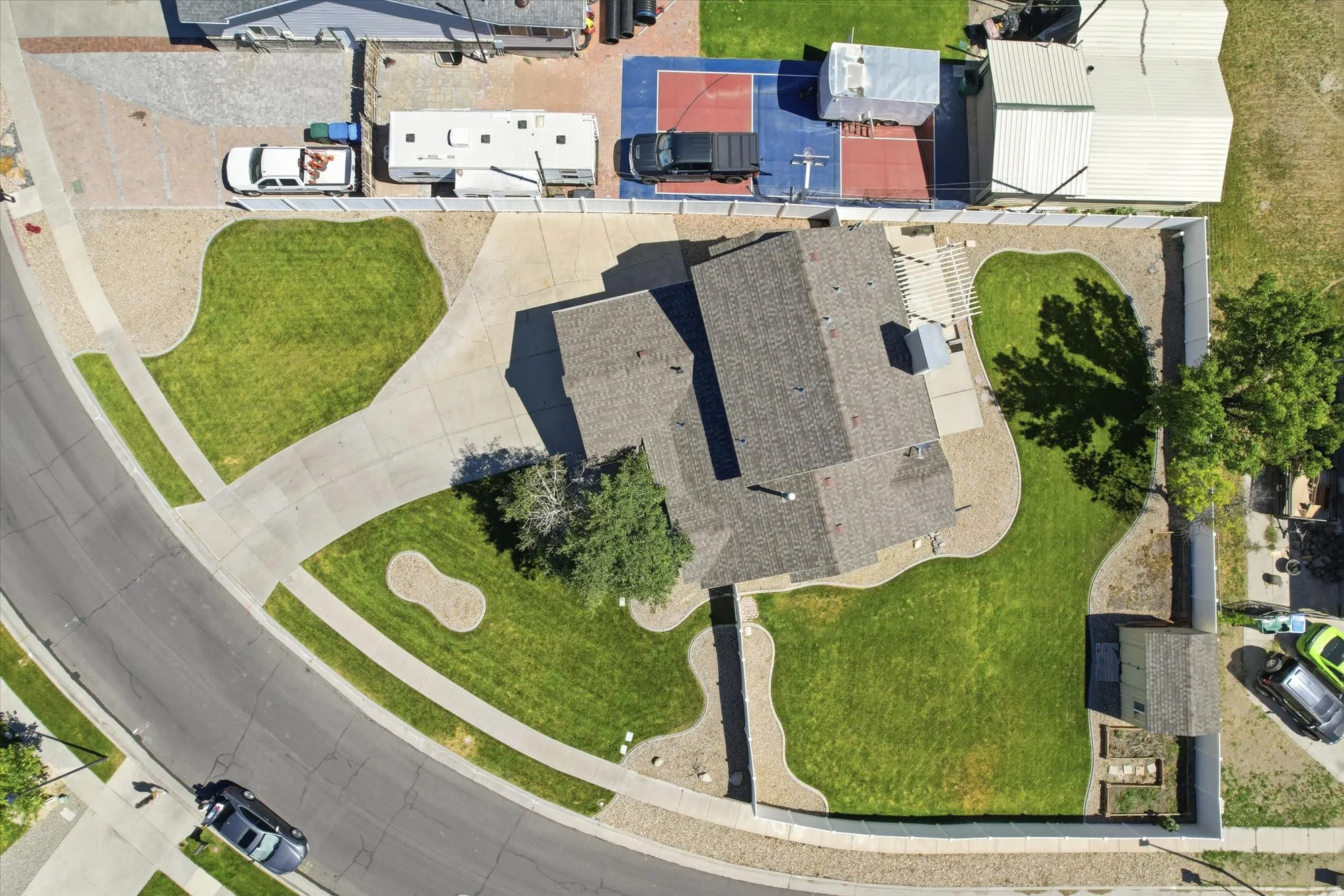 Paved driveway leading to a residence with a shingle roof and a rear pergola