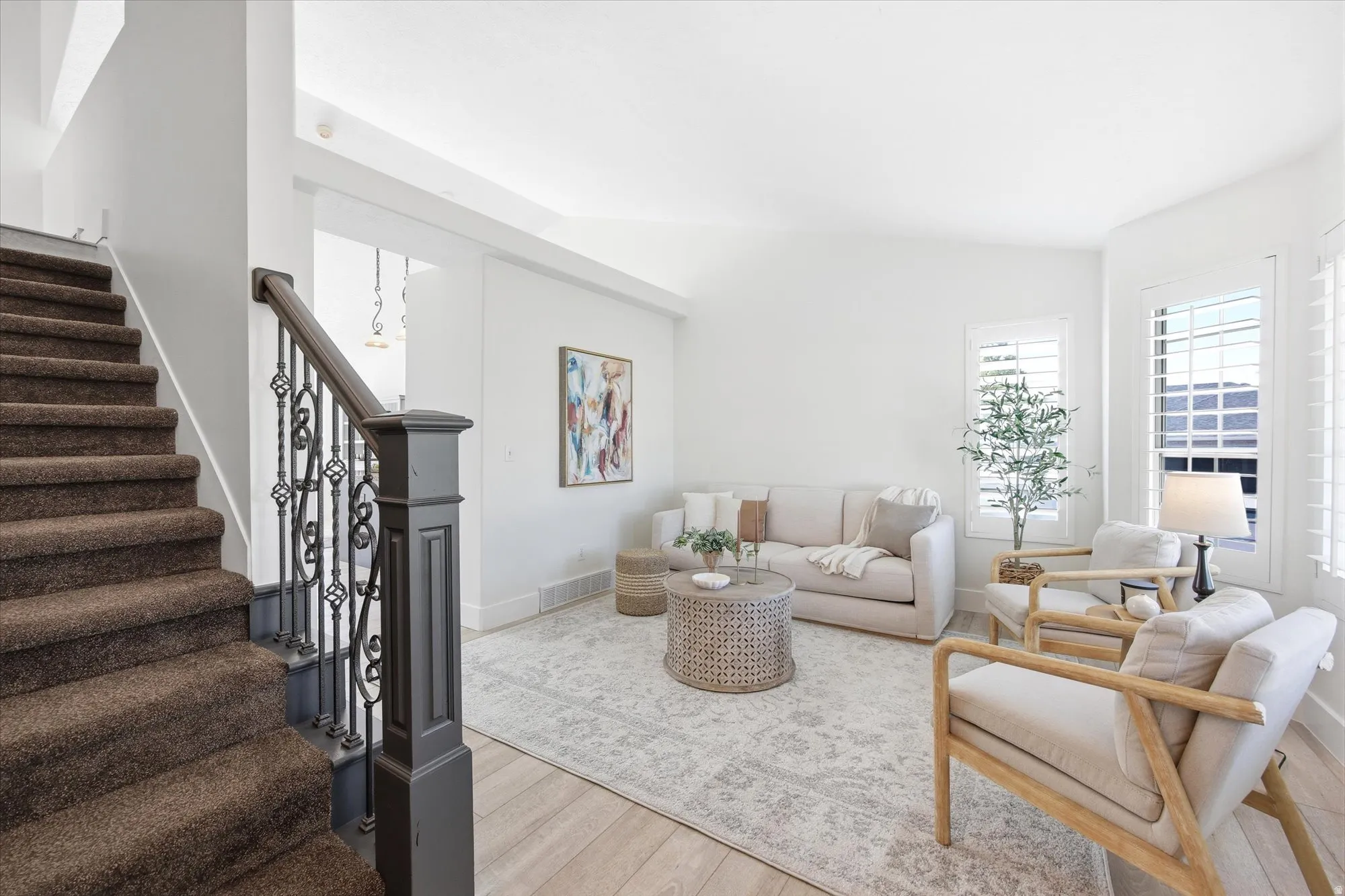 Inviting living area featuring light wood-finish flooring, plantation shutters, and a white color palette
