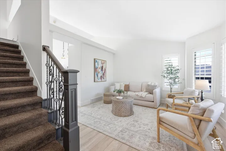 Inviting living area featuring light wood-finish flooring, plantation shutters, and a white color palette