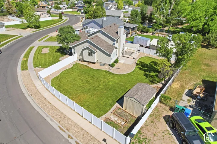 Expansive fenced backyard featuring a manicured lawn, established trees, and a dedicated storage shed