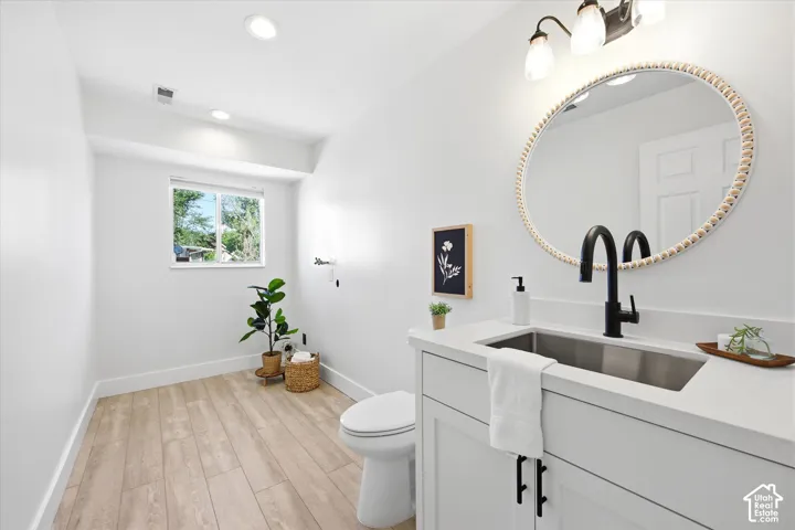 Contemporary bathroom featuring a white vanity with a stainless steel undermount sink, a matte black faucet, and a round decorative mirror