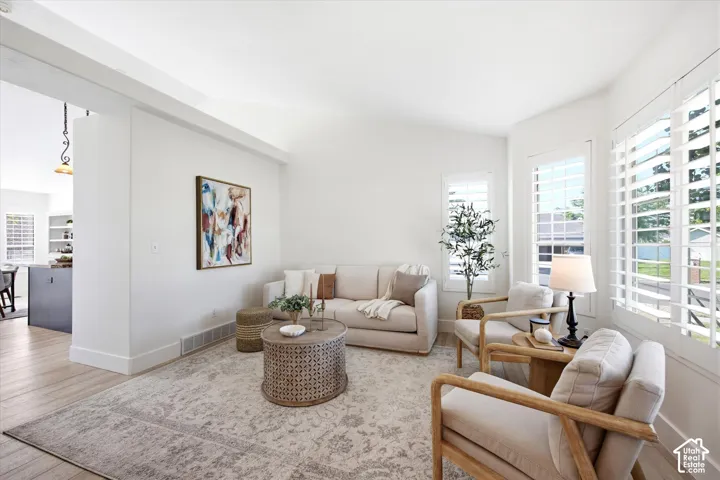 Bright living area featuring white walls, vaulted ceilings, and wood-finish flooring