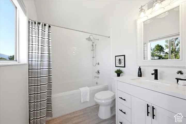 Bright bathroom featuring a white vanity with an integrated sink, a dark faucet, and a large mirror