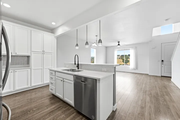 Modern kitchen island featuring a stainless steel sink, black gooseneck faucet, and integrated dishwasher