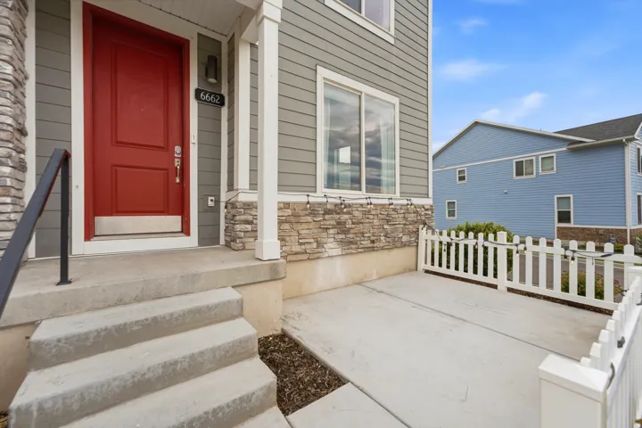 Inviting front entrance featuring a vibrant red door, a black outdoor sconce, and white house numbers