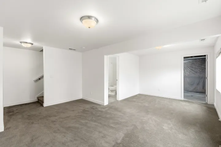 Spacious room featuring neutral carpeting, white walls, and bright ceiling-mounted light fixtures