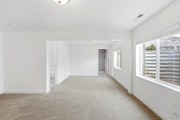 Spacious room featuring neutral carpeting, white walls, and multiple windows with white trim