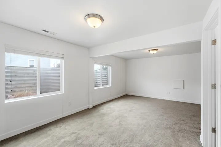 Spacious room featuring neutral carpeting and white painted walls