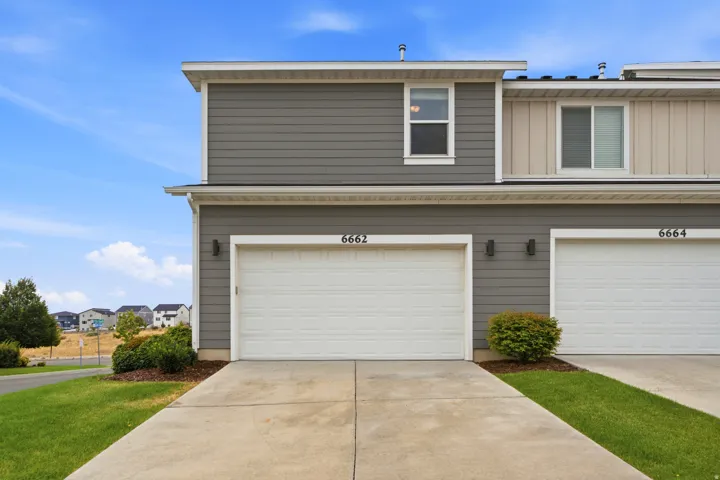 Modern townhome exterior featuring gray horizontal siding and a white garage door