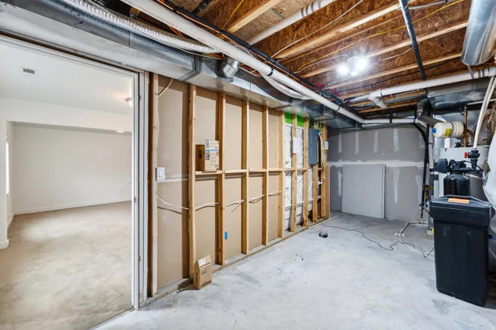Unfinished basement area featuring exposed ceiling joists, concrete flooring, and partial wall framing