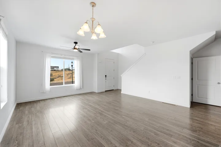 Spacious interior featuring wood-finish flooring, a large window, and a ceiling fan