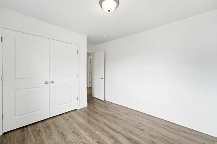 Interior room featuring wood-finish flooring, crisp white walls, and a recessed ceiling light fixture