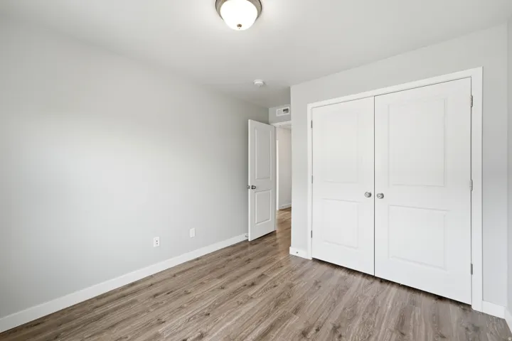 Spacious room featuring wood-finish flooring, light gray wall paint, white baseboards, and a semi-flush mount ceiling light