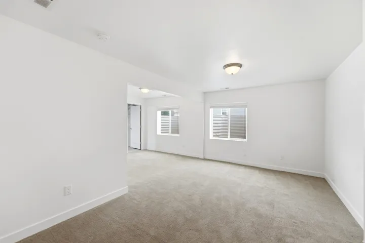 Spacious room featuring neutral carpeting, white walls, and a semi-flush mount ceiling light