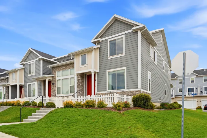 Contemporary townhome featuring gray siding, stone veneer accents, and a red entry door