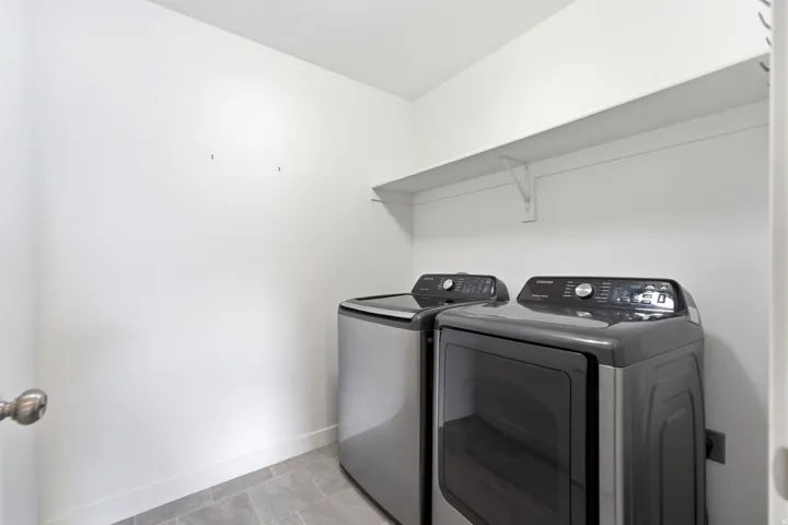 Laundry area featuring a built-in shelving unit, white walls, and a tiled floor