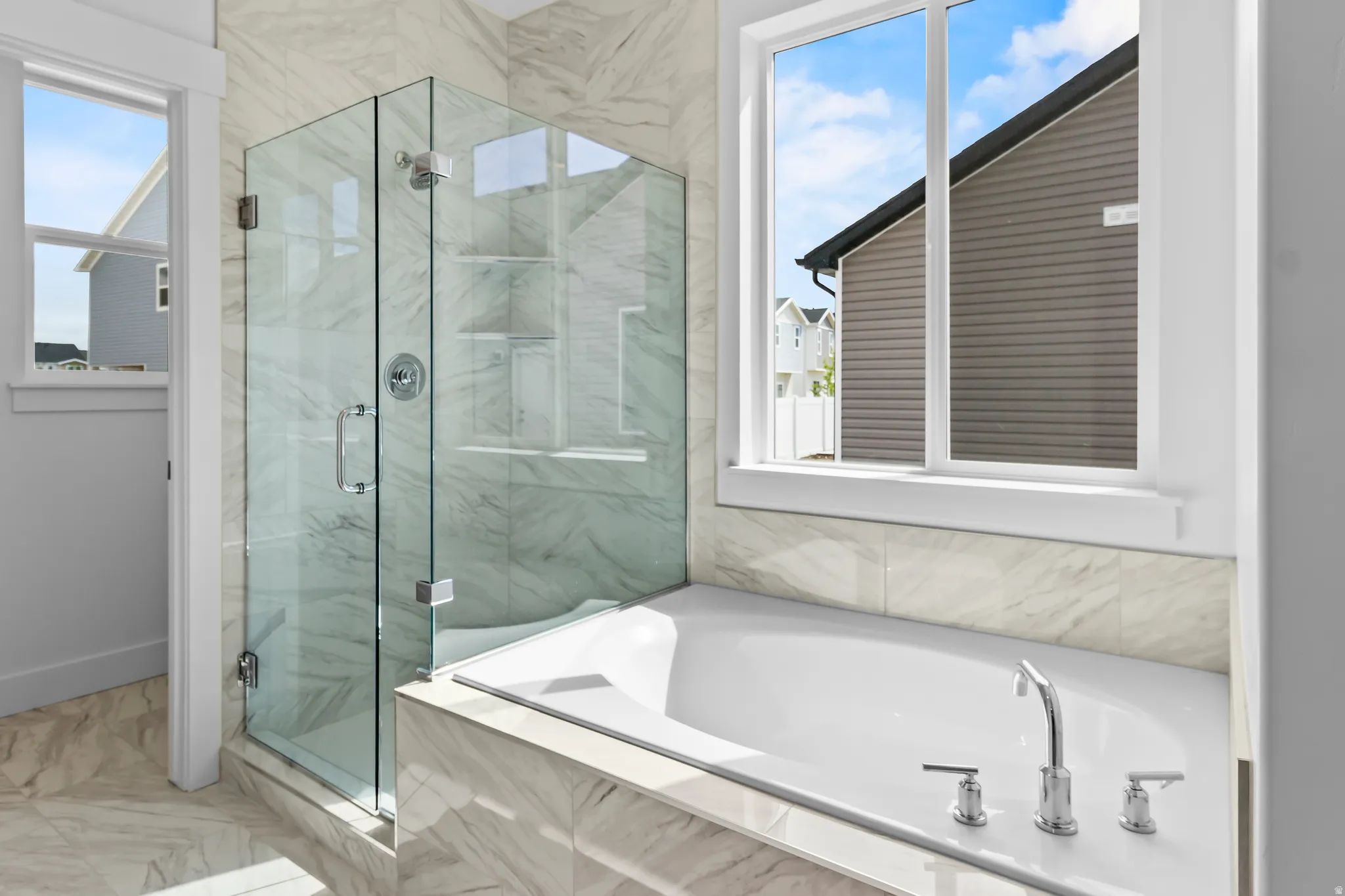 Built-in bathtub with chrome fixtures, glass-enclosed shower, and full-height tiled walls