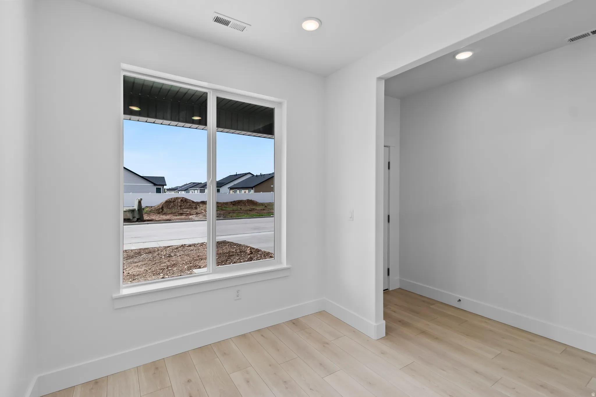 Spacious room featuring light wood-finish flooring and a large window