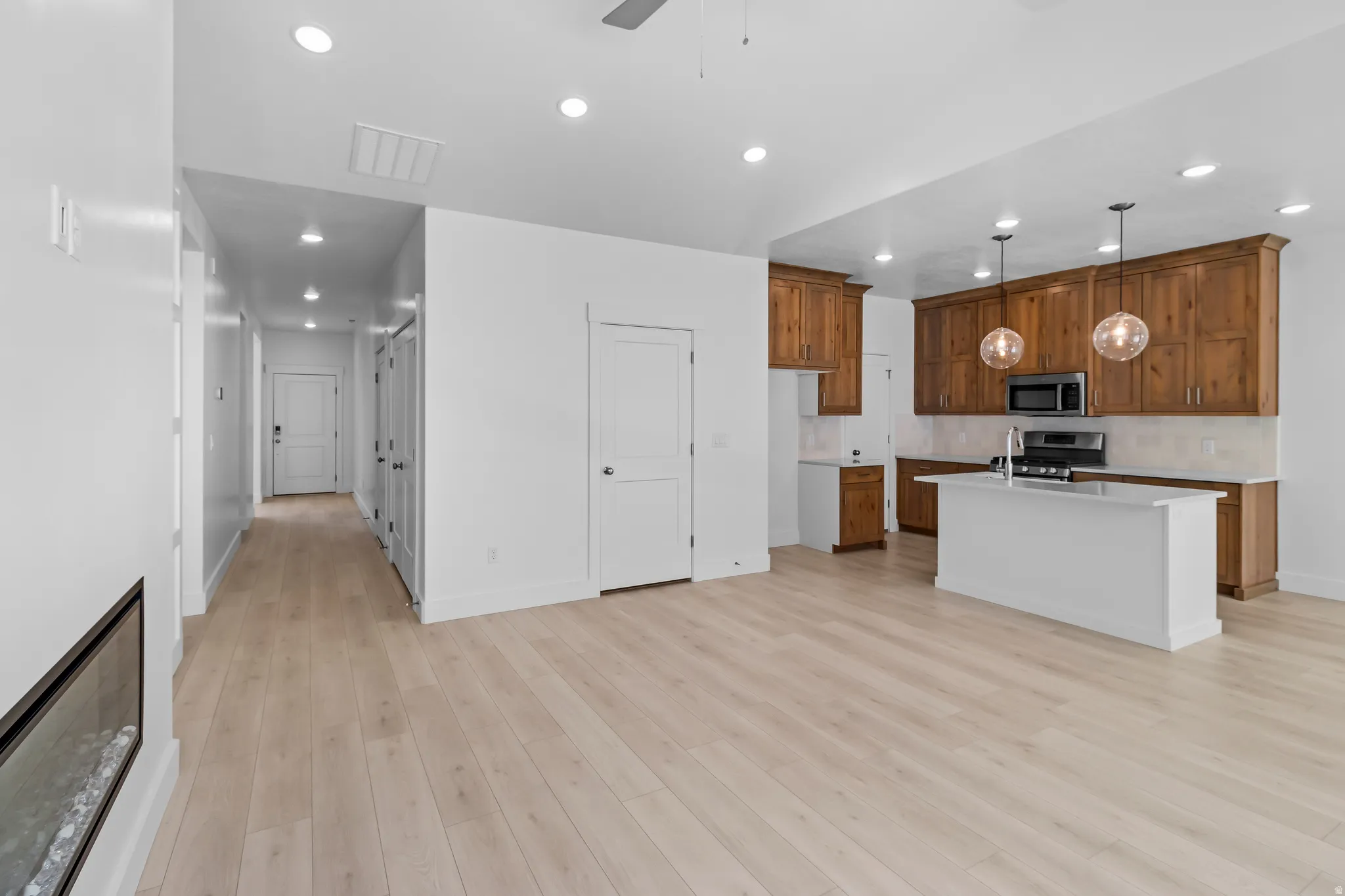 Open-concept living area featuring light wood-finish flooring and a contemporary linear fireplace