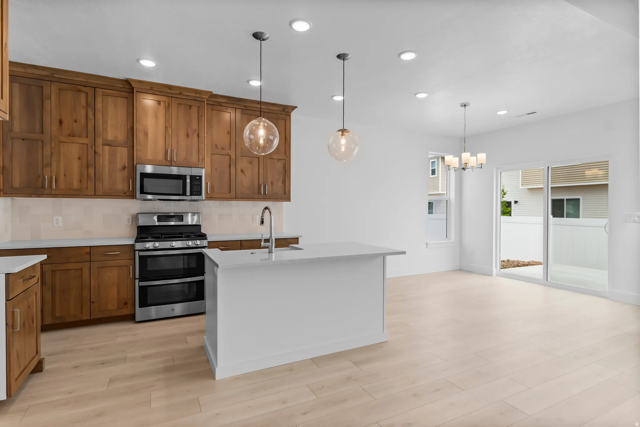 Open-concept kitchen featuring wood cabinetry, stainless steel appliances, and an island with a sink