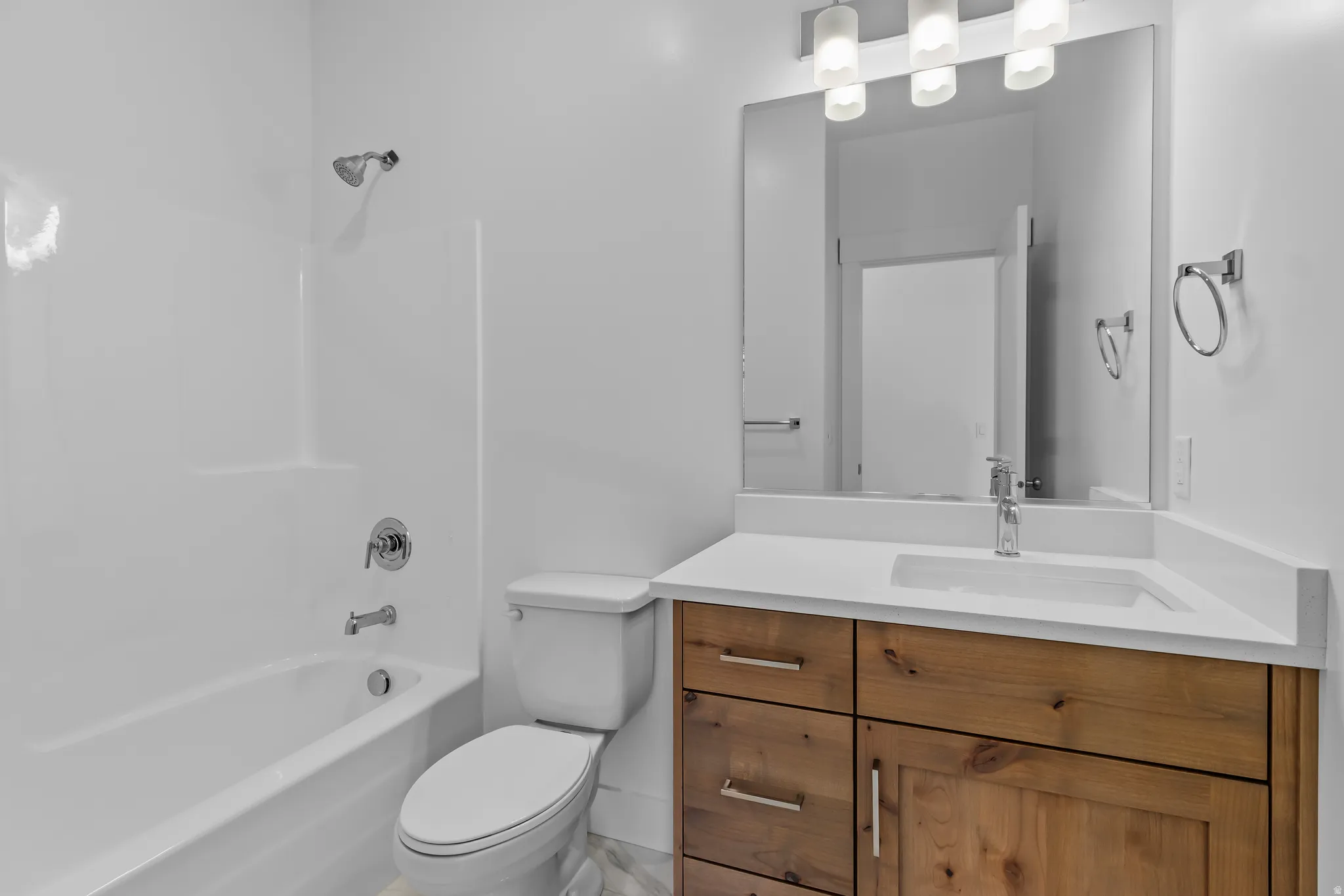 Modern bathroom featuring a wood-finish vanity with ample storage, integrated sink, and white countertop