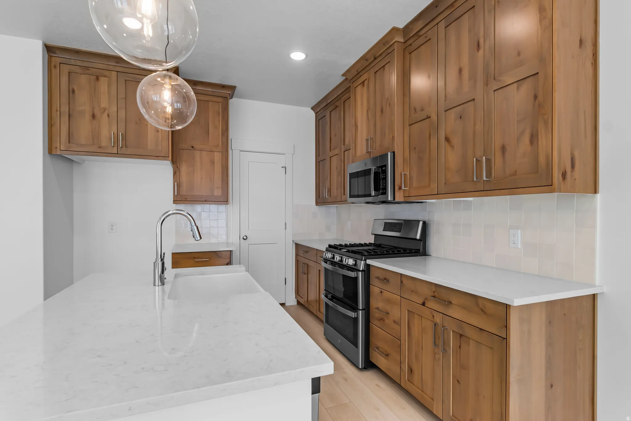 Open-concept kitchen featuring wood cabinetry, light-toned countertops, and a subway tile backsplash