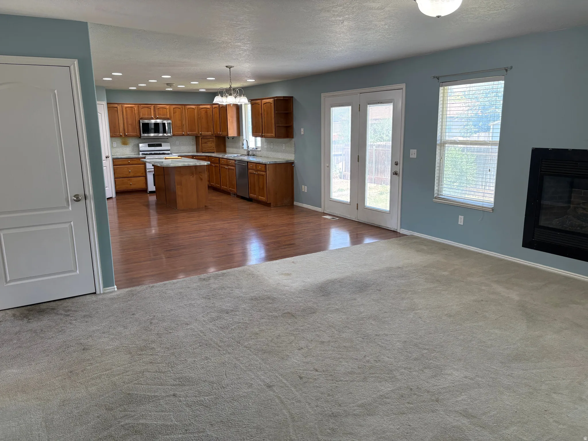 Open-concept kitchen and living area featuring wood-finish flooring, a central island, and stainless steel appliances