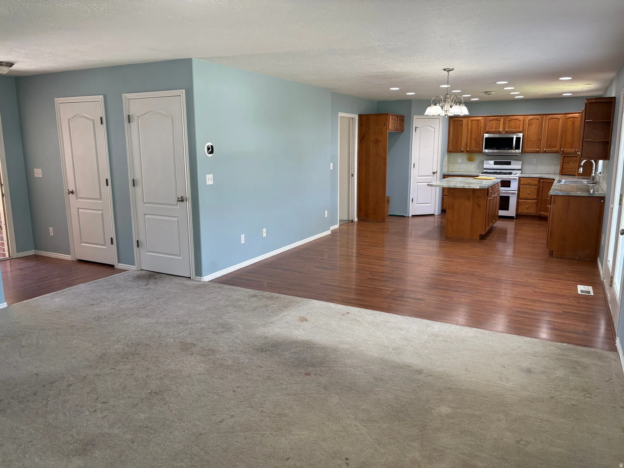 Open-concept interior featuring wood-finish flooring in the kitchen, light blue wall paint, and recessed lighting