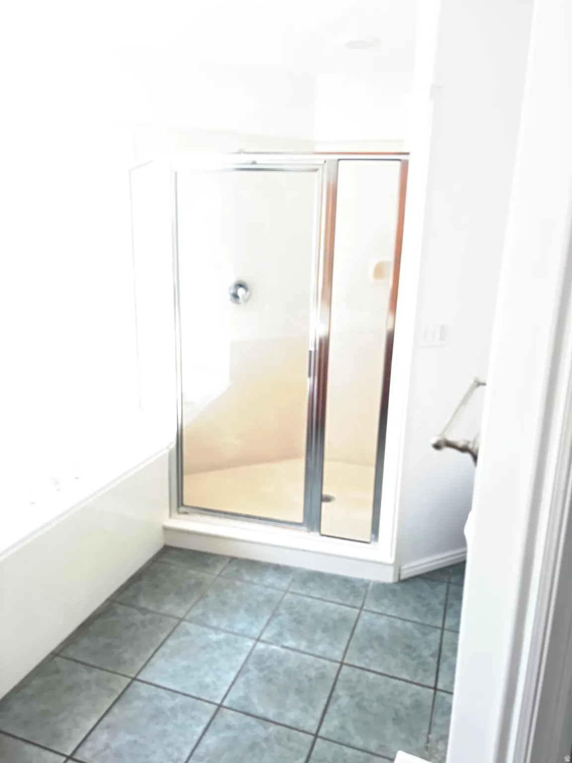 Shower enclosure with chrome frame, glass panels, and tile flooring