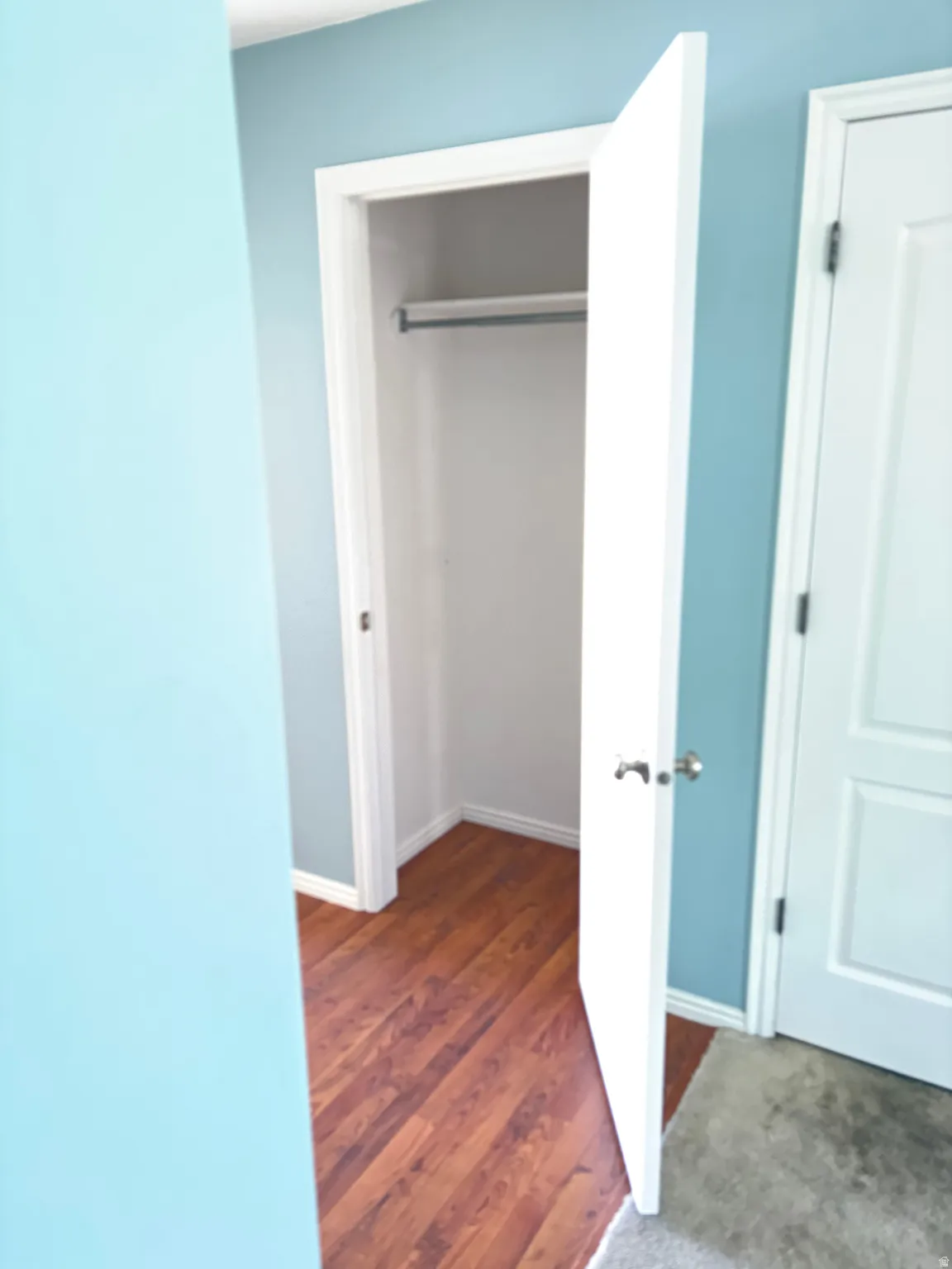 Open closet featuring a metal hanging rod and wood-finish flooring