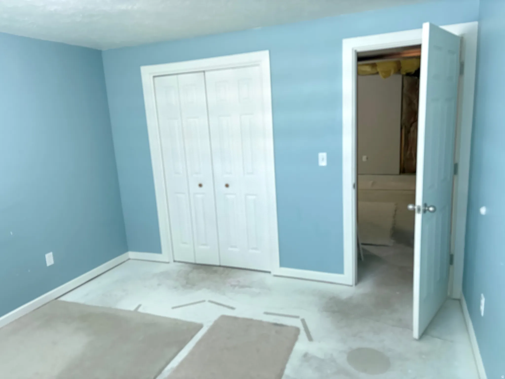 Room featuring light blue walls, white trim, and a white bi-fold closet door