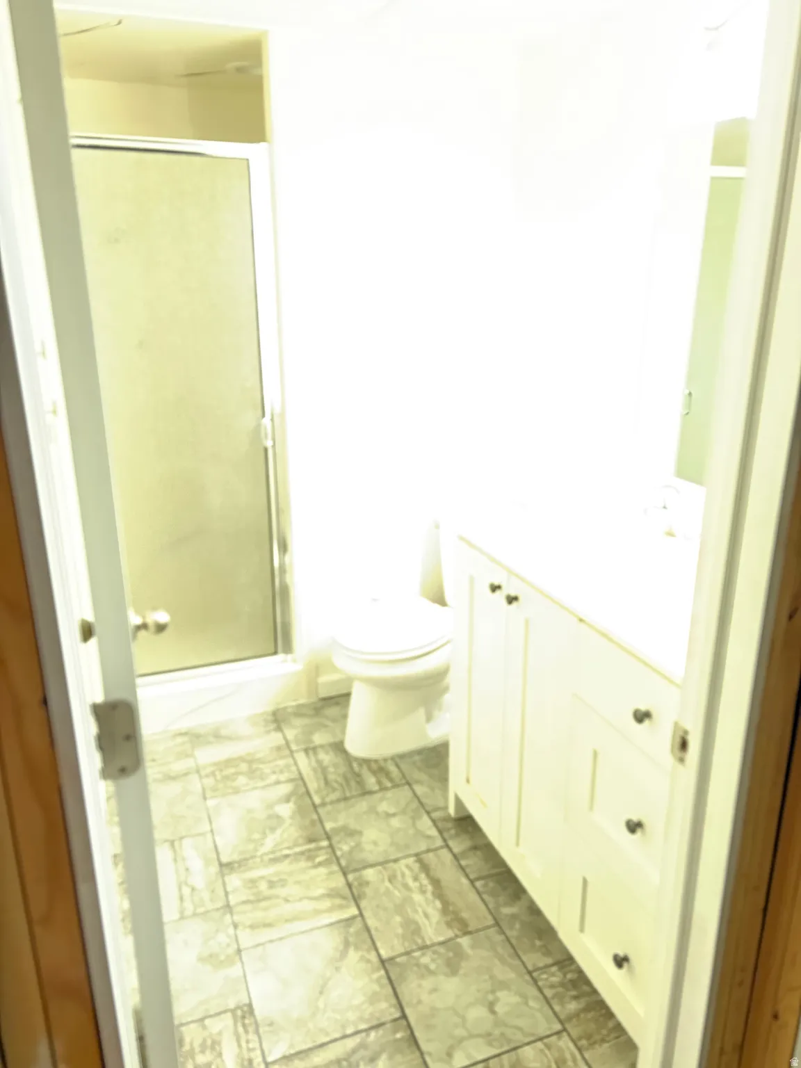 3/4 basement bathroom with cultured marble shower and glass shower door.
