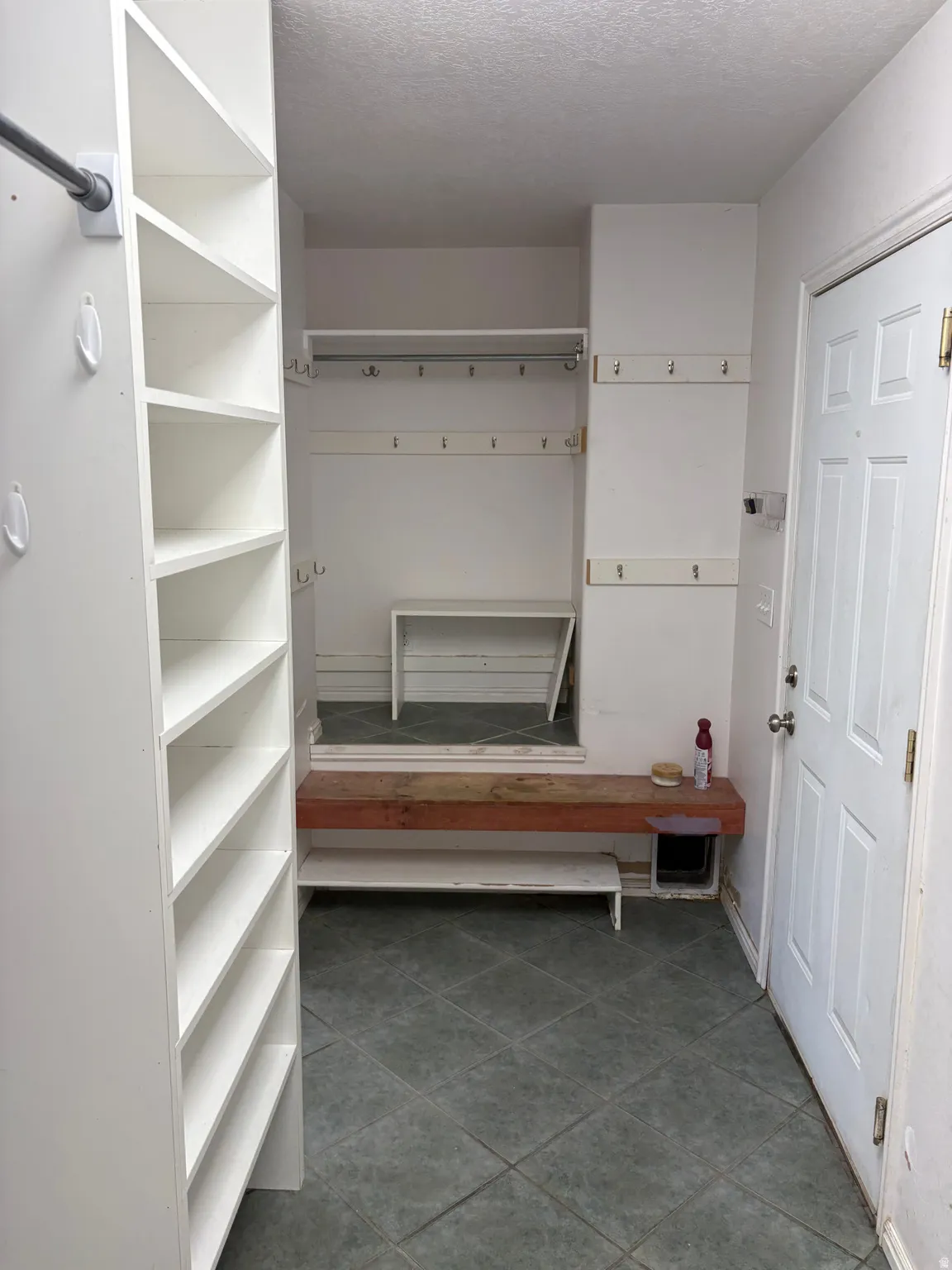 Entryway featuring a white paneled door, built-in shelving, storage hooks, and square tile flooring