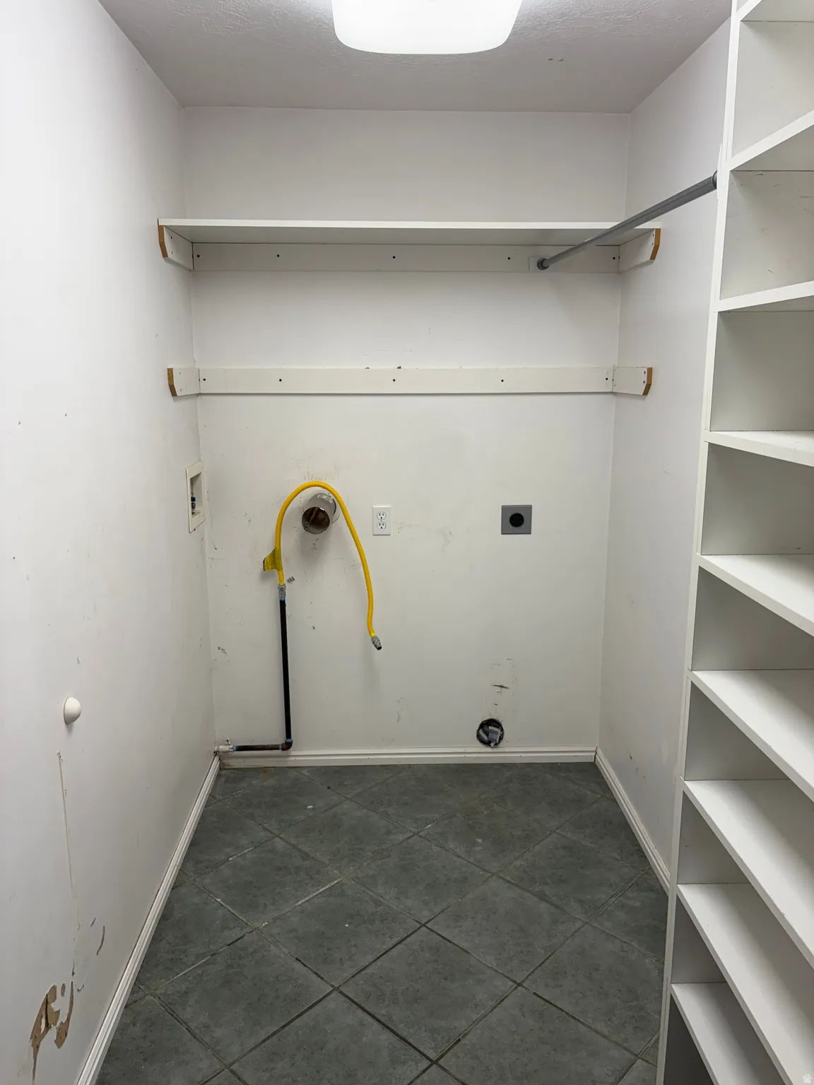 Laundry area featuring tiled flooring, built-in shelving, a clothes rod, and utility hookups