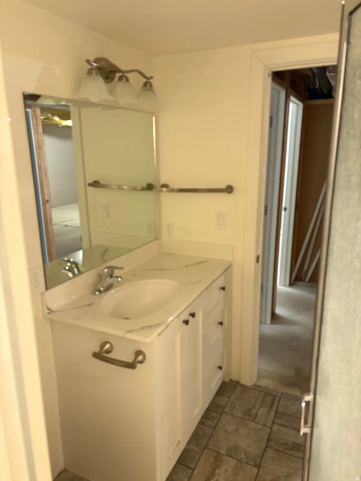 Bathroom vanity featuring a white cabinet base, a countertop with a subtle marble-like pattern, and an integrated white sink