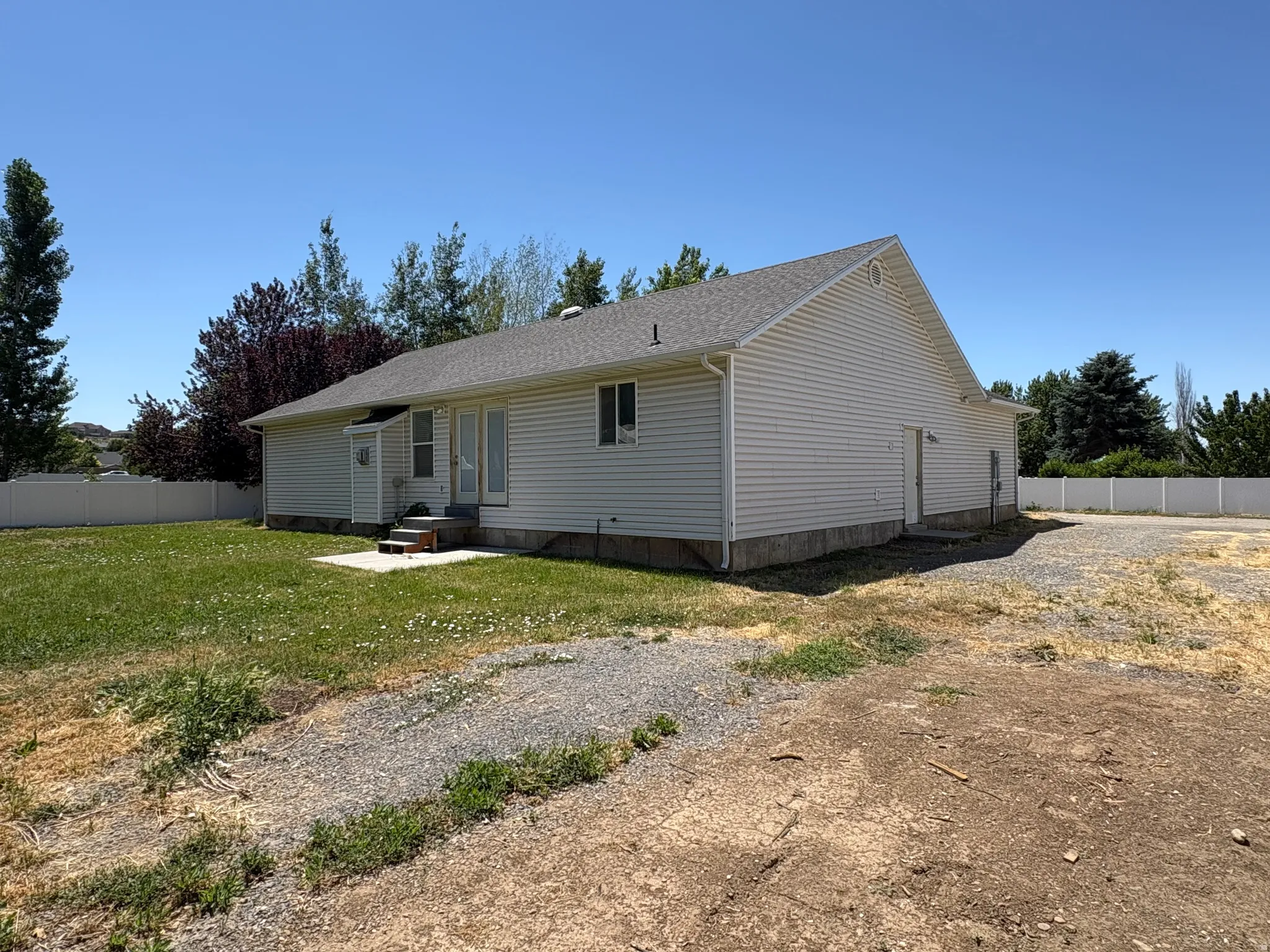 Rear exterior featuring white vinyl siding and a gray shingle roof