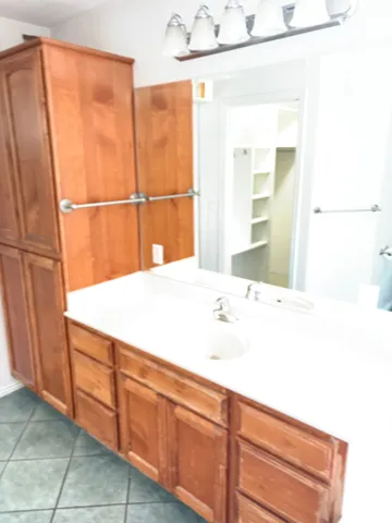 Master Bathroom vanity featuring wood-finish cabinetry, and tiled flooring